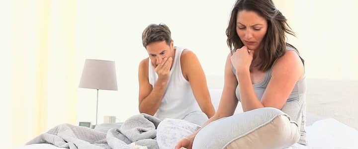 man and woman sitted on bed